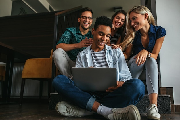 Una foto de un grupo de amigos felices mirando una computadora portátil