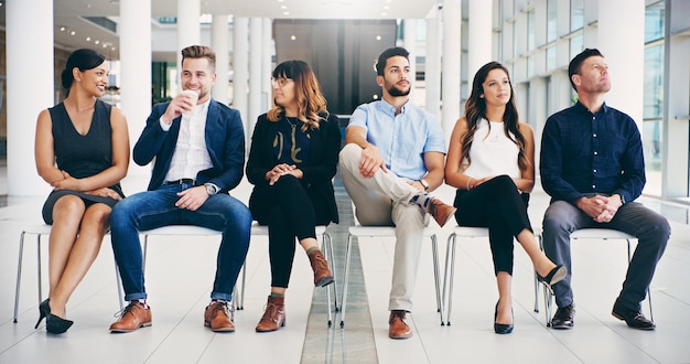 Foto de un grupo de diversos empresarios esperando en fila en una oficina moderna