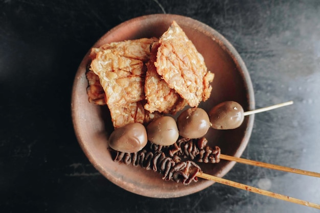 Una foto de la guarnición contiene intestino de pollo satay o sate usus ayam tempeh frito y huevos satay o sate telur puyuh comida tradicional indonesia