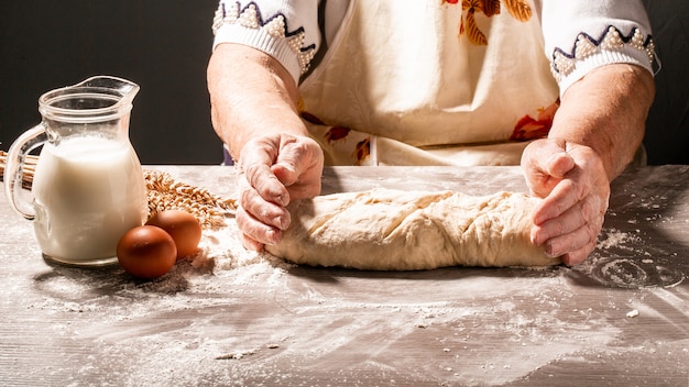 Foto de harina y manos de mujeres con salpicaduras de harina. Cocinar pan Amasar la masa. Aislado sobre fondo oscuro Espacio vacío para texto