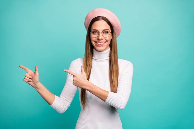 Foto de hermosa dama guapa dedos directos venta anuncio banner espacio vacío increíble precio bajo oferta especificaciones de desgaste gorra rosa boina cuello alto blanco aislado fondo de color verde azulado