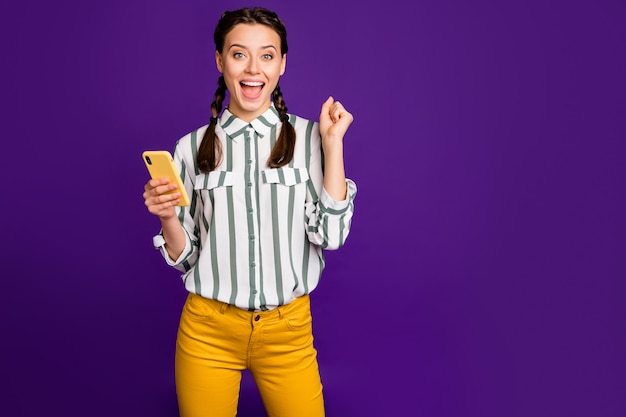 Foto de la hermosa dama loca sosteniendo la lectura de teléfono post positivos buenos comentarios y le gusta celebrar usar camisa a rayas pantalones amarillos aislado fondo de color púrpura