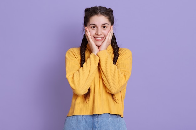 Foto de hermosa emocionada divertida joven pequeña con palmeras en las mejillas