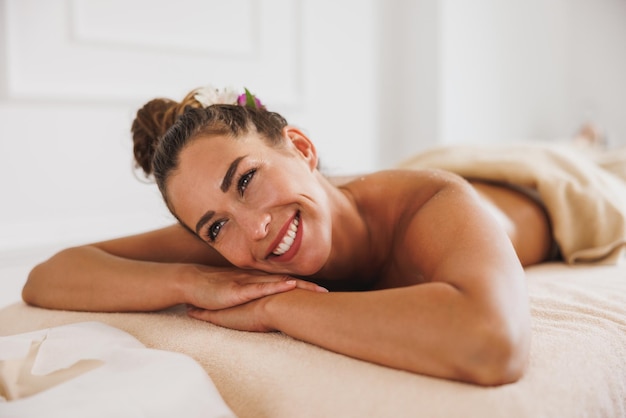 Una foto de una hermosa joven disfrutando de un masaje relajante en el salón de belleza.