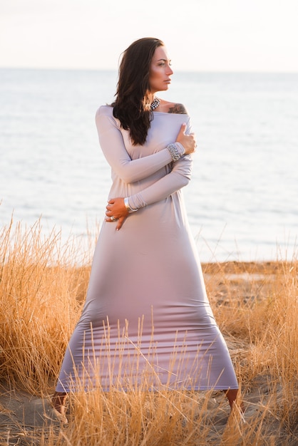 Foto de una hermosa joven elegante en vestido largo de moda en la playa