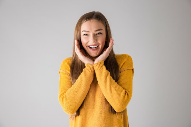 Foto de una hermosa joven feliz aislada sobre pared gris.