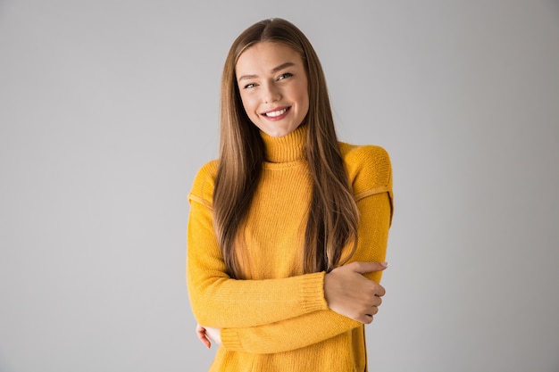 Foto de una hermosa joven feliz aislada sobre pared gris.