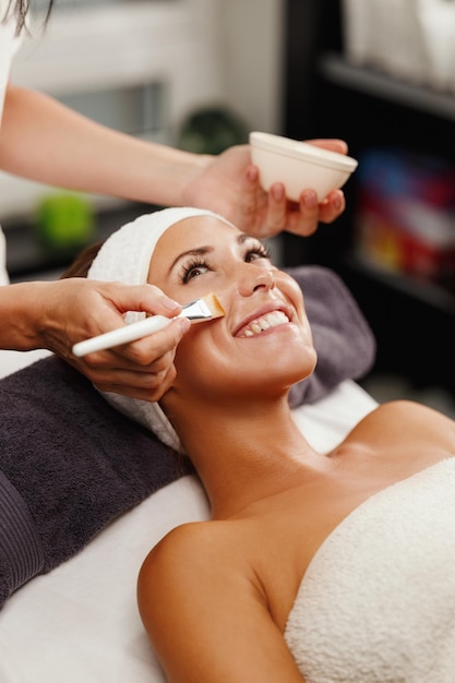 Foto de una hermosa joven recibiendo un tratamiento de máscara facial en el salón de belleza.