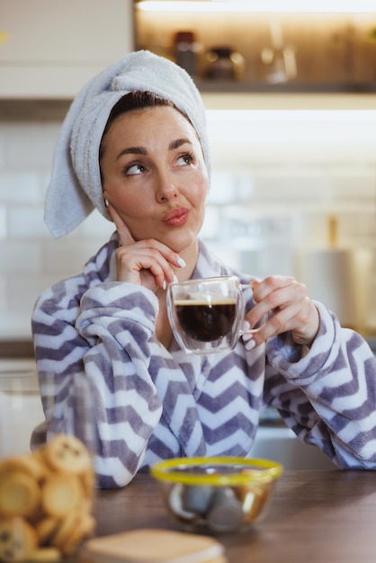 Foto de una hermosa joven tomando una taza de café en la cocina de casa.