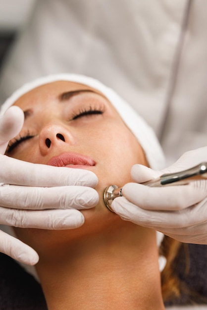 Una foto de una hermosa joven con un tratamiento facial de microdermoabrasión en el salón de belleza.