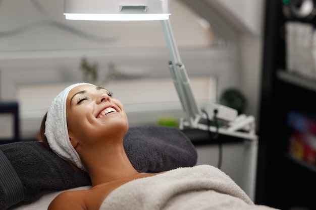 Una foto de una hermosa joven con un tratamiento facial en el salón de belleza.