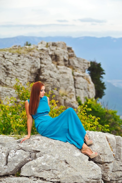 Foto hermosa y linda chica con una hermosa figura en vestido de noche de pie en la montaña