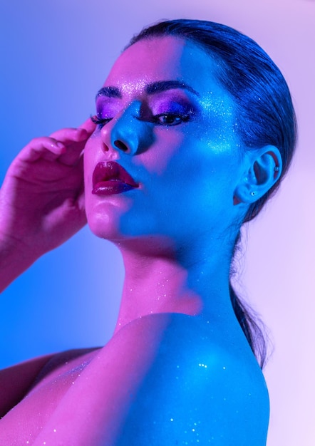 Foto de hermosa modelo morena en el estudio con filtros de color Resplandor de belleza de moda Cara de primer plano de una hermosa mujer brunete en luz de neón púrpura y azul