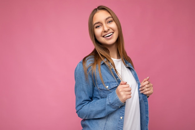 Foto de hermosa mujer adulta sonriente positiva con ropa elegante que se encuentran aisladas sobre fondo de colores con espacio de copia mirando a la cámara.