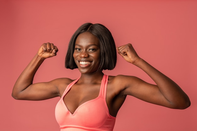Foto de una hermosa mujer afroamericana en sujetador rosa que muestra sus bíceps