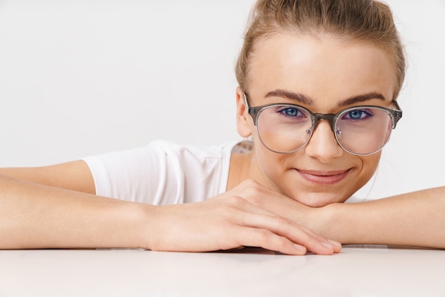 Foto de hermosa mujer divertida en anteojos sonriendo mientras se inclina sobre la mesa