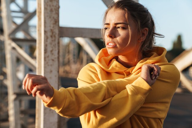 Foto de una hermosa mujer joven increíble fitness deportes hacer ejercicios de estiramiento al aire libre.