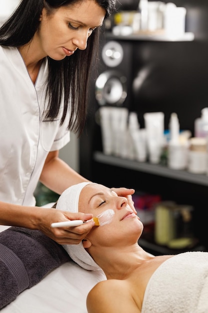 Foto de una hermosa mujer madura que recibe un tratamiento de máscara facial en el salón de belleza.