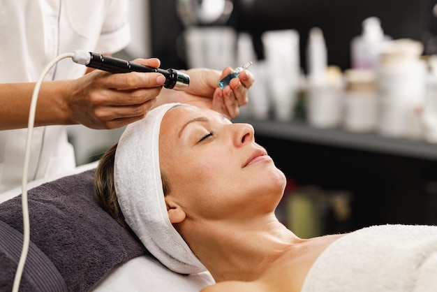 Foto de una hermosa mujer madura en un tratamiento de mesoterapia facial sin agujas en el salón de belleza.