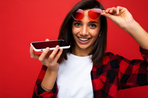 Foto de hermosa mujer morena joven feliz sonriente vistiendo elegante camisa roja, camiseta blanca y roja