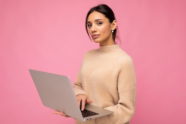 Foto de hermosa mujer morena joven seria vistiendo suéter beige con equipo