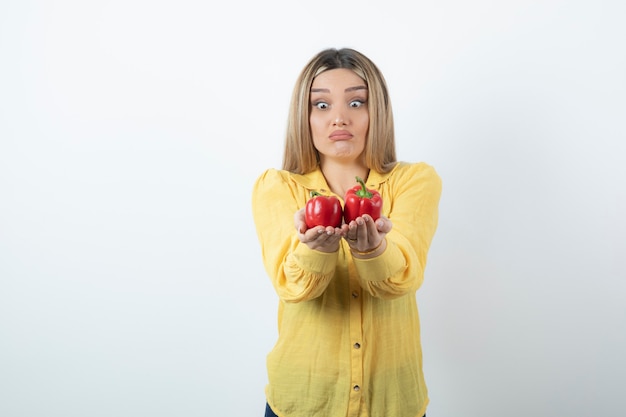 Foto de hermosa mujer rubia sosteniendo pimientos rojos