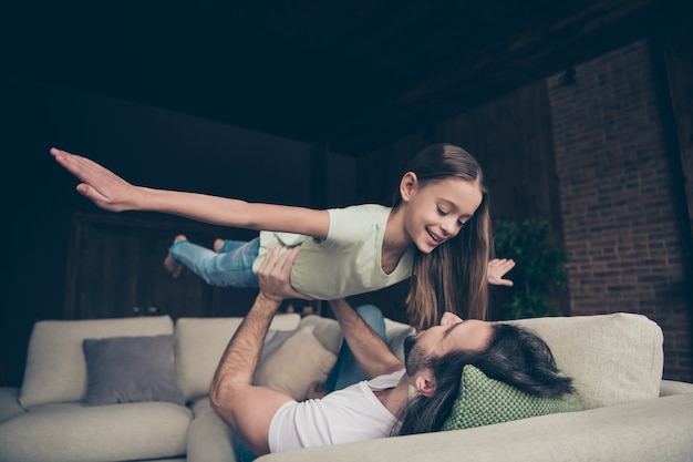 Foto de hermosa niña adorable y apuesto joven papá sentarse en un cómodo sofá