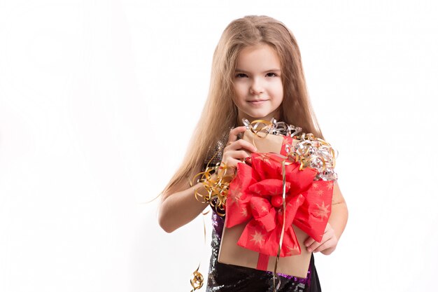 Foto de hermosa niña con caja de regalo en la pared blanca