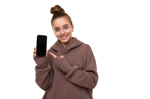 Foto de una hermosa niña linda con cabello oscuro y un moño en una sudadera con capucha marrón con capucha sosteniendo un