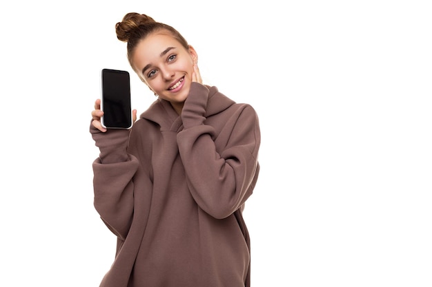 Foto de una hermosa niña linda feliz con cabello oscuro y un moño en una sudadera con capucha marrón con capucha sosteniendo