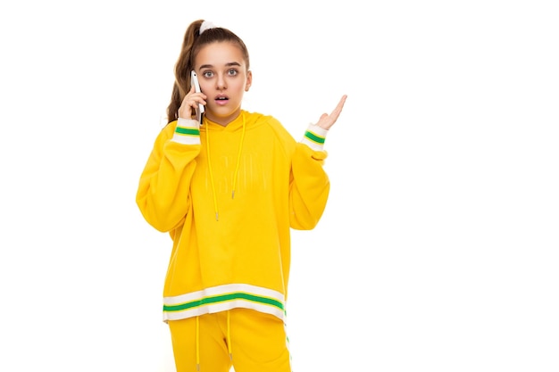 Foto de una hermosa niña sorprendida y conmocionada con cabello oscuro con una cola de caballo en un elegante amarillo