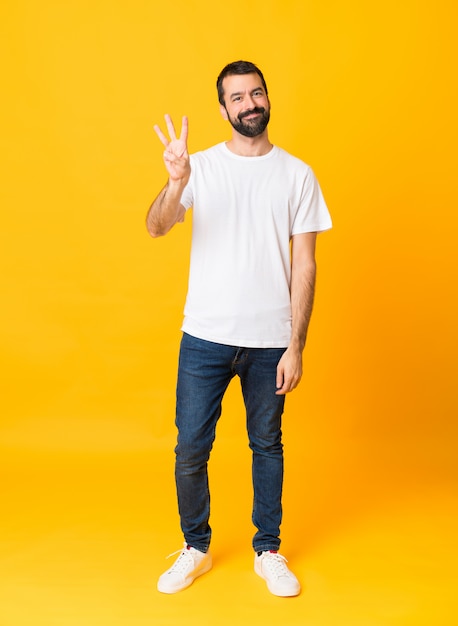Foto de hombre con barba sobre amarillo aislado feliz y contando tres con los dedos