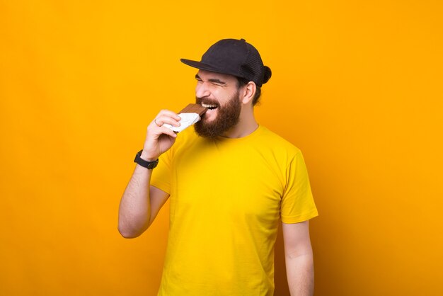 Una foto de un hombre barbudo comiendo chocolate y siendo feliz