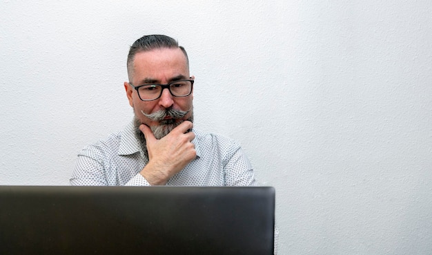 Foto de un hombre barbudo hipster trabajando con una computadora portátil en casa