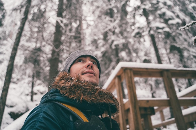 Foto del hombre en el bosque de invierno en el puente de madera