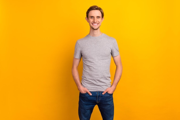 Foto de hombre de buen aspecto positivo manos bolsillos jeans sonriendo aislado sobre fondo de color brillante