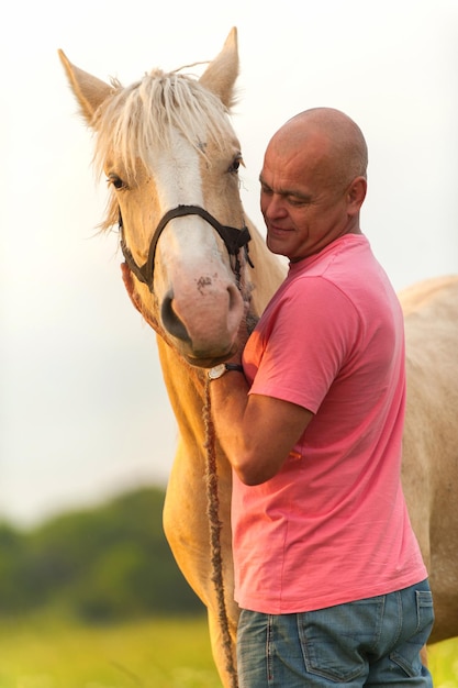 Foto hombre calvo camina con un caballo en el campo