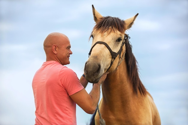 Foto hombre calvo camina con un caballo en el campo