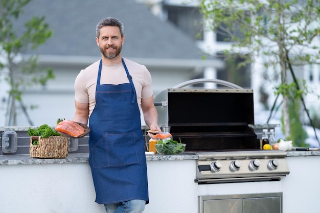 Foto del hombre cocinando salmón comida copia espacio anuncio hombre cocinando salmon en la parrilla