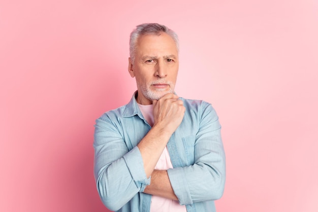 Foto de hombre de edad apuesto enfocado en el brazo, toque la barbilla, piensa en calma, reflexiona, aislado sobre fondo de color rosa.