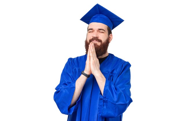 Foto de hombre estudiante de licenciatura y gorro de graduación rezando