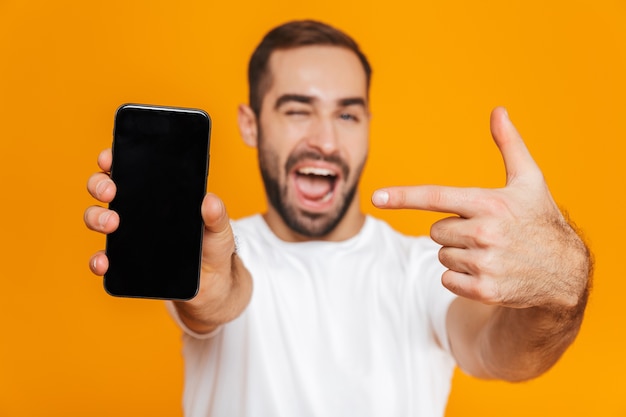 Foto de hombre feliz de 30 años en ropa casual sonriendo y sosteniendo el teléfono inteligente, aislado