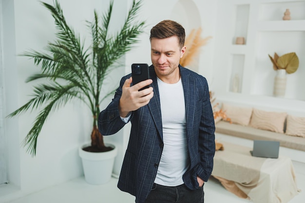 Foto de un hombre feliz y guapo con una chaqueta clásica hablando por teléfono móvil y sonriendo Trabajo remoto en casa