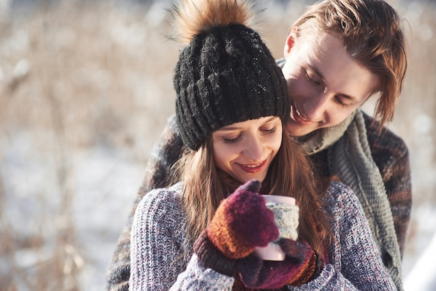 Foto del hombre feliz y de mujer bonita con tazas al aire libre en invierno