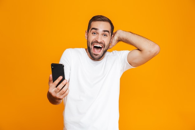 Foto de hombre guapo de 30 años en ropa casual con smartphone, aislado