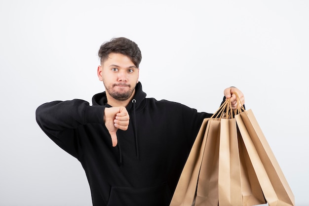 Foto de hombre guapo en sudadera con capucha negra que lleva un montón de bolsas de artesanía