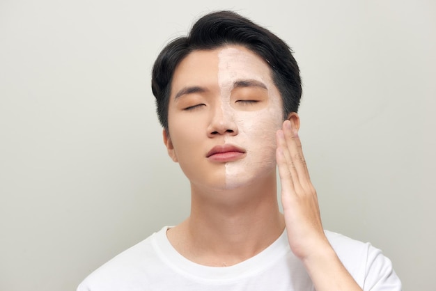 Foto de hombre con máscara de arcilla cosmética en su rostro aislado sobre fondo blanco.