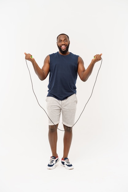 Foto de hombre masculino saltar la cuerda, joven musculoso haciendo ejercicio con saltar la cuerda en gris