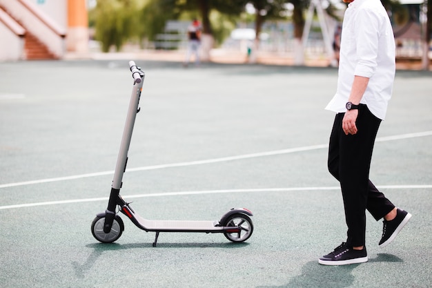 Foto de hombre moderno con scooter eléctrico en la calle.