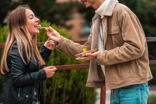 Una foto de un hombre y una mujer modernos disfrutando de la ciudad y comiendo deliciosos poffertjes frescos